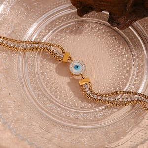 Macro view of triple-layered 18K gold-plated bracelet with evil eye and zircon details