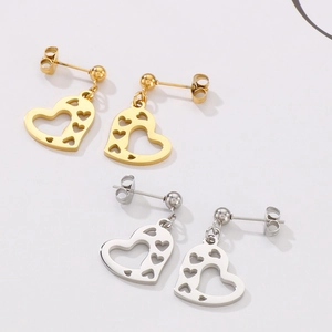 Detailed close-up of hollow heart-shaped earrings in polished gold and silver steel finish