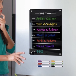 Close-up of black acrylic weekly planner with magnetic markers on a kitchen fridge