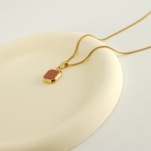 Détail macro d'un collier plaqué or 18 carats avec pendentif rectangulaire en pierre brune