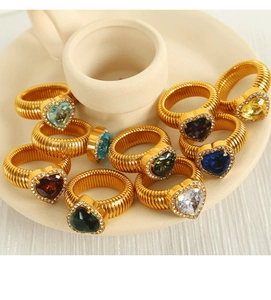 Detail view of colorful heart-shaped rings with textured gold bands on a ceramic dish