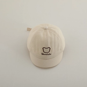 Gros plan détaillé sur la broderie d'ours et le texte d'une casquette beige pour bébé