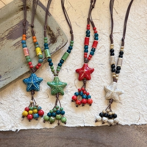 Gros plan de colliers en céramique en forme d'étoile avec perles et pompons colorés