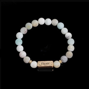 Detail of beaded natural stone bracelet with engraved bronze Faith metal charm
