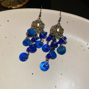 Detail of vintage ethnic long hook earrings with blue sequins and bronze floral metal