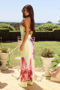 Detail of a floral satin backless maxi dress with pink orchids on a light yellow base