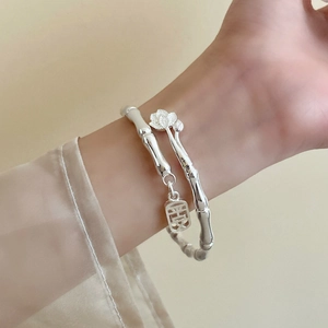 Detailed view of bamboo style silver bangle with lotus flower and safety pendant