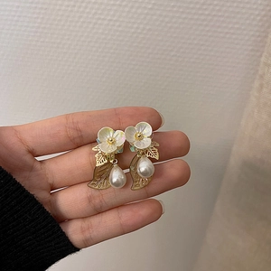 Detailed shot of floral earrings with gold leaf accents and teardrop pearls
