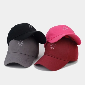 Close-up of four cotton baseball caps with minimalist sun embroidery in various colors