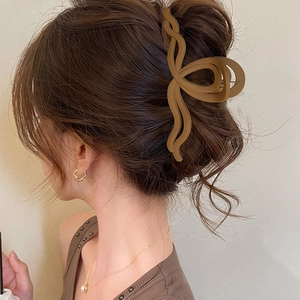 Dettaglio di una molletta per capelli opaca marrone ondulata su un elegante chignon moderno