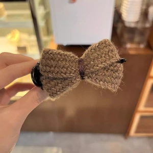 Close-up of brown knitted bow hair claw clip showing soft texture and handmade detail