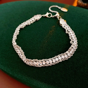 Close-up of a silver triple-strand chain bracelet with clear crystals on green velvet