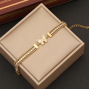 Close-up of golden butterfly bracelet with white shell inlay and double rows of crystals