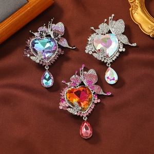 Detailed view of three crystal butterfly brooches with heart stones and teardrop tassels