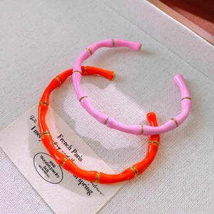 Dettaglio di bracciali in smalto a forma di bambù nei colori rosa ciliegio e arancione