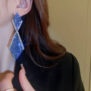 Detailed view of blue rhinestone geometric long tassel earrings on a model with sparkling finish