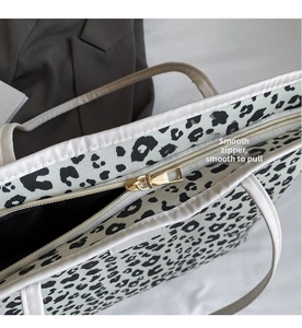 Gros plan de la fermeture éclair dorée et du motif léopard sur ce sac fourre-tout
