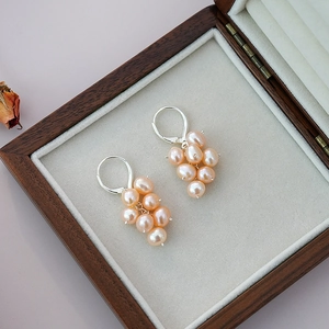 Silver grape cluster earrings with natural pink pearls on a wooden jewelry display box