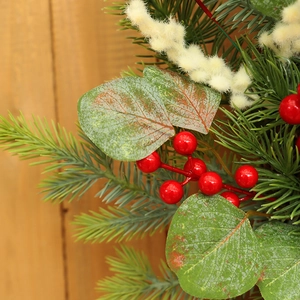 Christmas wreath with red berries, pine needles and frosted eucalyptus on wood background
