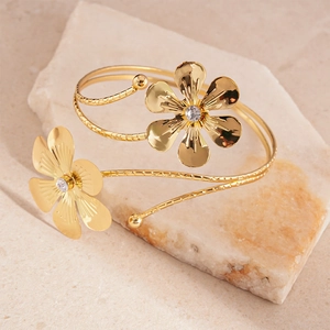 Close-up of gold flower bracelet featuring detailed petals, rhinestones and spiral band