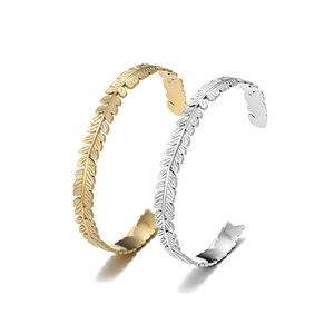 Detailed view of gold and silver laurel leaf feather cuff bangles in stainless steel