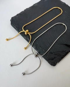 Detail of adjustable snake bone chain bracelets in gold and silver with slider beads