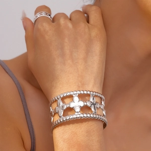 Detailed macro view of silver hollow floral open bracelet with beaded edges and polished finish