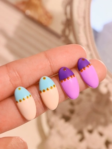 Macro detail of colorful enamel stud earrings with contrast polka dots and glazed finish