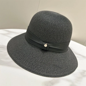 Detail of elegant black straw sun hat with ribbon and small gold metal charm