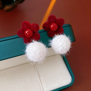 Macro view of flocking flower earrings with white plush balls on a jewelry box