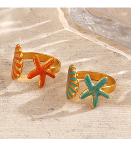 Detail of adjustable starfish and seashell rings in orange and turquoise enamel on sand