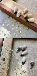 Detailed view of gold embossed flower and butterfly nail stickers on gradient nail tips