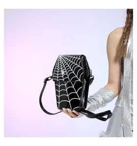 Close-up of black spider web pattern crossbody bag worn by a model in futuristic style