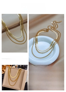 Detail of a triple-layered gold chain necklace featuring snake and curb style links