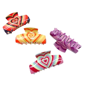 Set of four colorful acrylic heart-patterned hair claws on a clean white background