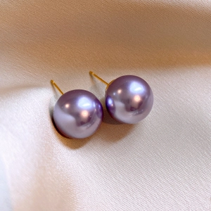Elegant purple pearl stud earrings with gold needles on silk background, vintage style
