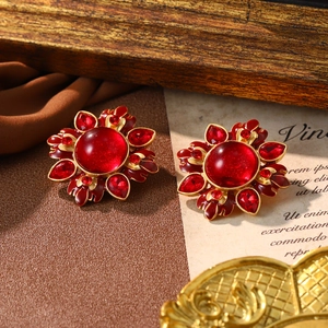 Macro shot of vintage style gold-toned flower earrings with vibrant red crystals