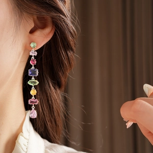 Close-up of dangling earrings featuring colorful teardrop and geometric cubic zirconia stones