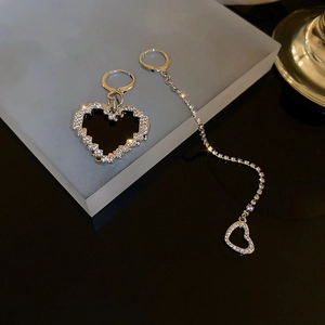 Detail of asymmetric silver earrings with black pixel heart and sparkling rhinestone chain