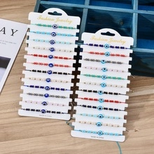 Detail of woven bracelets with evil eye beads in multiple colors on wood background