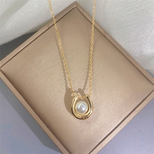 Elegant gold U-shaped pendant necklace with pearl on jewelry box and soft tulle