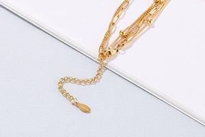 Close-up of a gold multi-layer bracelet with lobster clasp and S.STEEL engraving tag