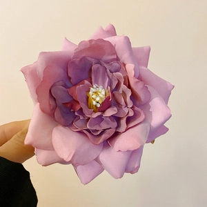 Detail of purple fabric rose hair clip with realistic petals and stamen texture