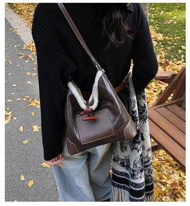 Detail of faux shearling trim and toggle button on a brown leather hobo shoulder bag