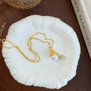 French romantic golden necklace featuring a white pearl and star pendant on a shell tray