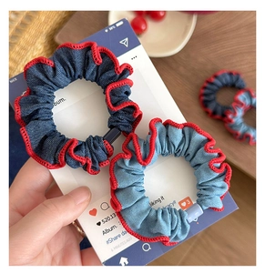 Close-up of blue denim scrunchies with contrast red stitched edges and buckle detail