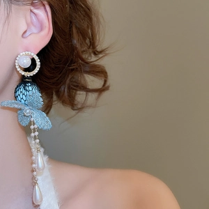 Close-up of light blue lace butterfly earrings with cascading pearl tassels on model