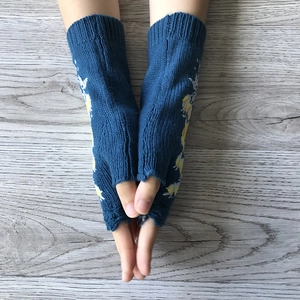 Close-up of blue knitted fingerless gloves with delicate yellow floral embroidery