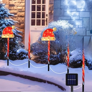 Solar Christmas North Pole hat stake lights with red white striped poles on snowy ground