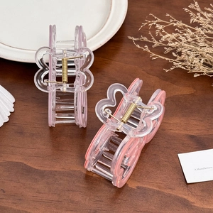 Pink acetate hollow butterfly claw clips on a wooden table with elegant home decor